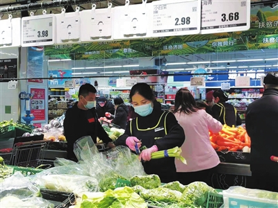 新百连超大阅城店，工作人员在整理蔬菜。