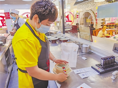 <p>　　银川市金凤区西竹拌面大阅城店工作人员给打包好的外卖餐品贴食品封签。</p>