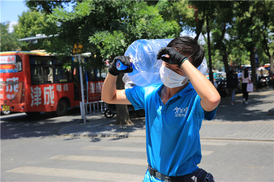 7月19日,吴忠市利通区一位送水小哥在烈日下扛着桶装水,为客户送去"
