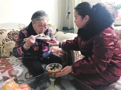 何金兰老人吃到社区送的饺子，非常开心。