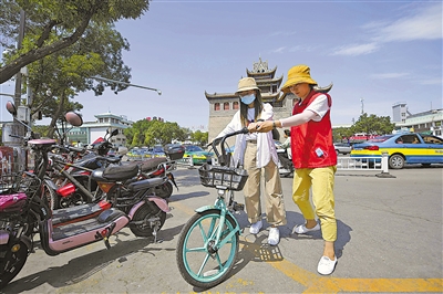     鼓楼社区志愿者引导市民规范停车。