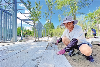 <p>　　小微公园施工现场，工人认真铺设行道砖。</p>