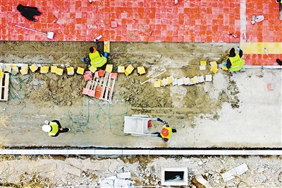 3月19日，银川市兴庆区熙春巷（北京路—上海路）慢行绿道工程施工现场，工人们为硬化路面铺设地砖。该慢行绿道工程北起上海路，南至北京路，全长1003米。工程建设融入海绵城市、园林城市理念，将对道路两侧人行道进行改造，新建绿化隔离带、彩色沥青非机动车道、透水砖人行道等。工程整体计划5月底完成。改造完成后，熙春巷将增加1条车道，可按双向三车道通行,并实现机非分离。     本报记者 马楠 王洋 摄