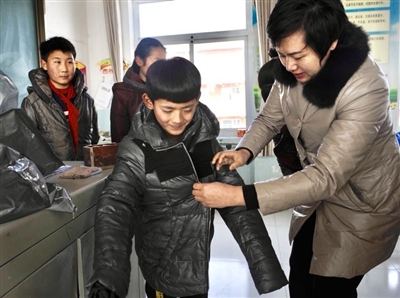 王玲给学生试穿新衣。本报记者  周丽芳   摄影报道