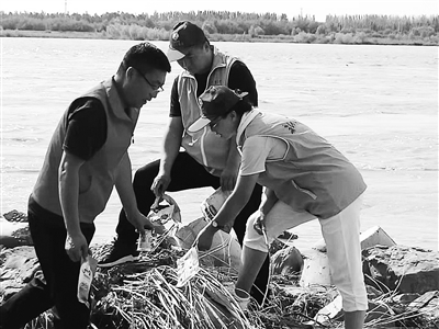 7月13日，黄河吴忠段的“民间河长”李小平与和志明带领50名志愿者，来到黄河边巡视河堤、捡拾垃圾，向河边烧烤的游客讲解安全及环保注意事项。　　　　　李淑香   摄