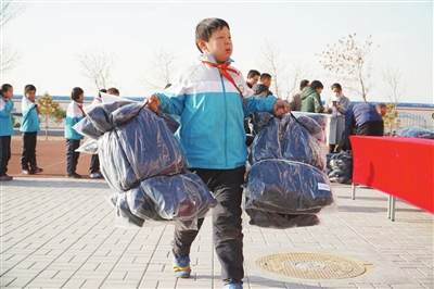     永宁县闽宁镇西滩小学的学生在搬运棉衣。这批棉衣共220件，由银川雷利祥电气公司捐赠。   本报记者    闵良    摄