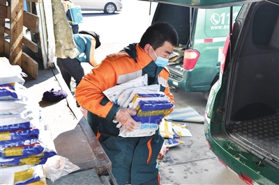 银川市邮政分公司工作人员将打包好的教材搬上投递车。