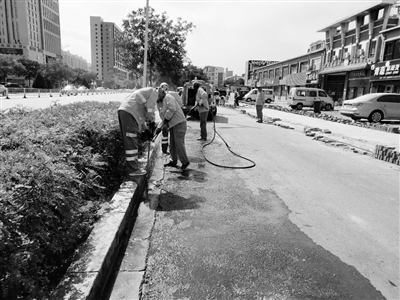 环卫工人正在清洗新华东街路面油渍。 本报记者    李辉    摄