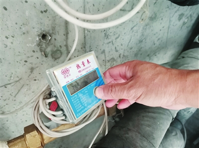 李先生查看热量表上的数据。本报记者  邱曦  摄