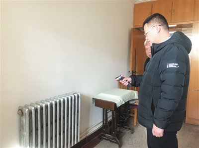 工作人员手持测温枪对橡民A区居民家中暖气片进行测温。本报记者  张艳丽  摄