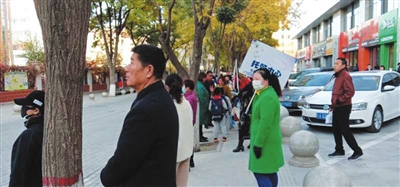 托管中心工作人员举着牌子在校外等着接学生。