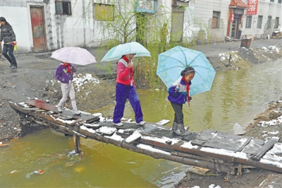<p>　　学生们下雨天走过临时搭建在红花渠上的木“桥”。（摄于2015年）</p>