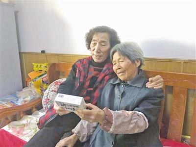 <p>　　刘春秀（左）在给王桂英读药品服用须知。</p>