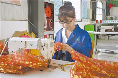 <p>　　吴忠市利通区扁担沟镇移民新村同利村扶贫车间内，女工娴熟地穿针引线，将金色抽绳嵌在喜糖袋子上。</p>
