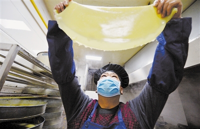 <p>　　天还蒙蒙亮，工人在操作间内仔细检查凉皮的生产质量。</p>