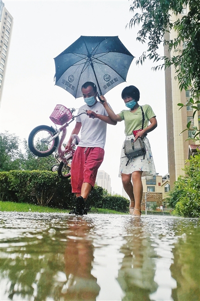银川市金凤区一小区内，居民在暴雨中前行。 本报记者  季正  摄