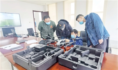 李波（右二）在修理无人机。 本报记者    安小霞    摄
