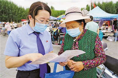 <p>灵武市人民检察院检察官在集市发放打击整治养老诈骗宣传手册。　本报记者　杨超　实习生　武治瑾　摄</p>