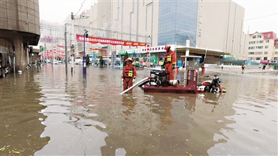 路面严重积水，消防救援人员持续排涝。消防部门供图
