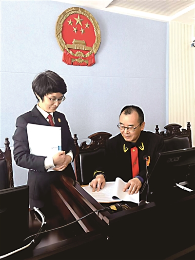 李民（右）审阅指导纪智的裁判文书。