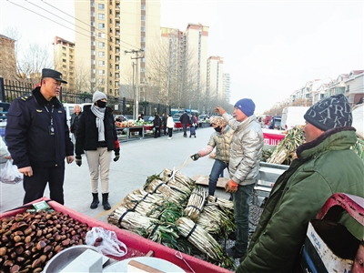 12月6日早晨，在庆丰街早市，长城中路执法中队中队长苏瑞（左一）询问流动商贩进入市场后的经营状况。