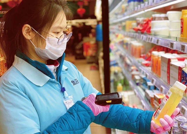 ▲图为某生鲜平台门店员工为商品扫码。图片来源：新民周刊