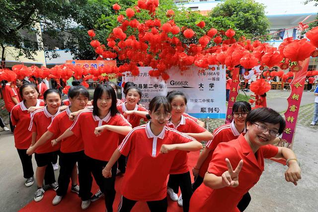 7月5日，在广西柳州市融安县第二中学，老师和学生在“顺利号”动车票前合影。