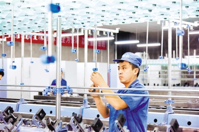 现代纺织扶贫产业园工人调试生产设备