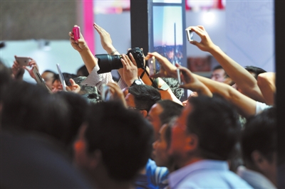 2015年9月3日，在银川市国际会展中心，市民们高举手机拍摄中阿博览会主宾国约旦的文艺表演。随着通信事业的迅速发展，手机已经从过去单纯的电话功能成为集电话、电脑、相机、信用卡等众多功能于一体的移动终端。