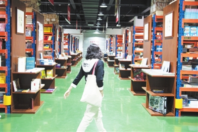 5月5日，在贺兰县德胜工业园区的新华书店德胜仓卖场，一位市民在书架间穿梭。该卖场由占地面积1600平方米的书店仓库转型而来，人们可以推着购物车，像在超市一样穿梭在书架间选购图书。卖场书籍总量超过10万册，还着重营造阅读环境，设置了阅读区、文创区等区域。    本报记者  季正  摄