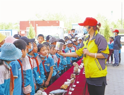 <p>　　→　志愿者向原隆小学学生展示矿石。</p>