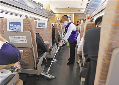 高铁服务人员穿梭在各个车厢，及时清扫车厢卫生，为旅客提供舒适、干净的乘车环境。本报记者 王猛 摄
