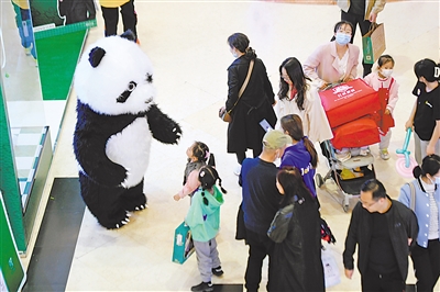 “五一”假期，在银川市新华百货CCpark购物广场，一名工作人员扮成“大熊猫”为来往的顾客送去欢乐。本报记者 马楠 王洋 摄