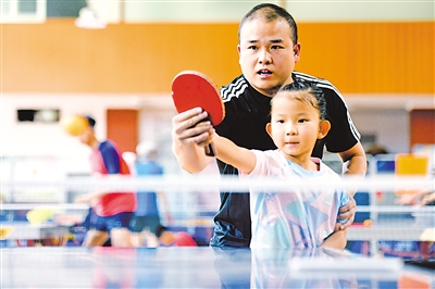 <p>徐新磊手把手教孩子打乒乓球。</p>