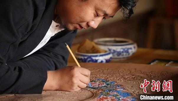 图为贾宏伟为皮画上色。　受访者供图 摄