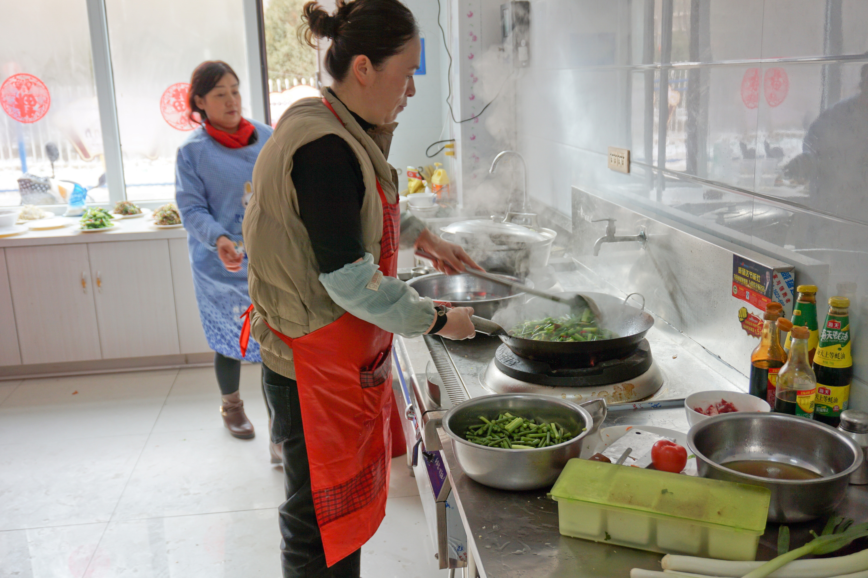 01-社区“老饭桌”工作人员正在忙碌的炒菜.jpg