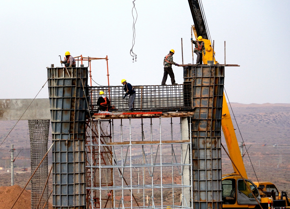 乌玛高速跨包兰铁路特大桥施工现场,工人正在安装墩柱模板.