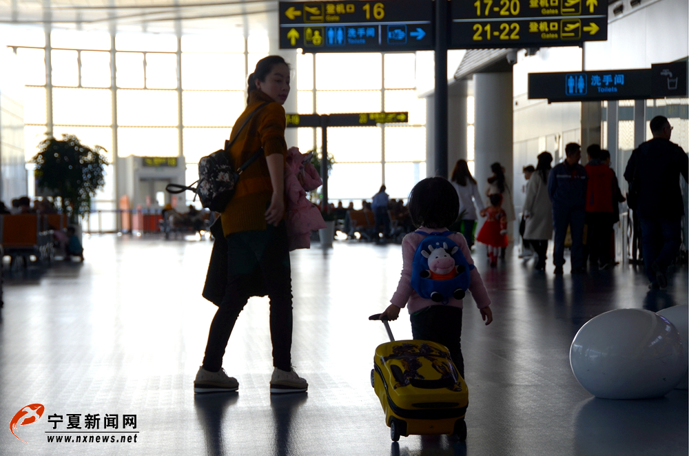 2月14日，大年三十，在银川河东国际机场航站楼，一位年轻的妈妈带着自己的宝宝匆匆前往值机台办理登机手续。