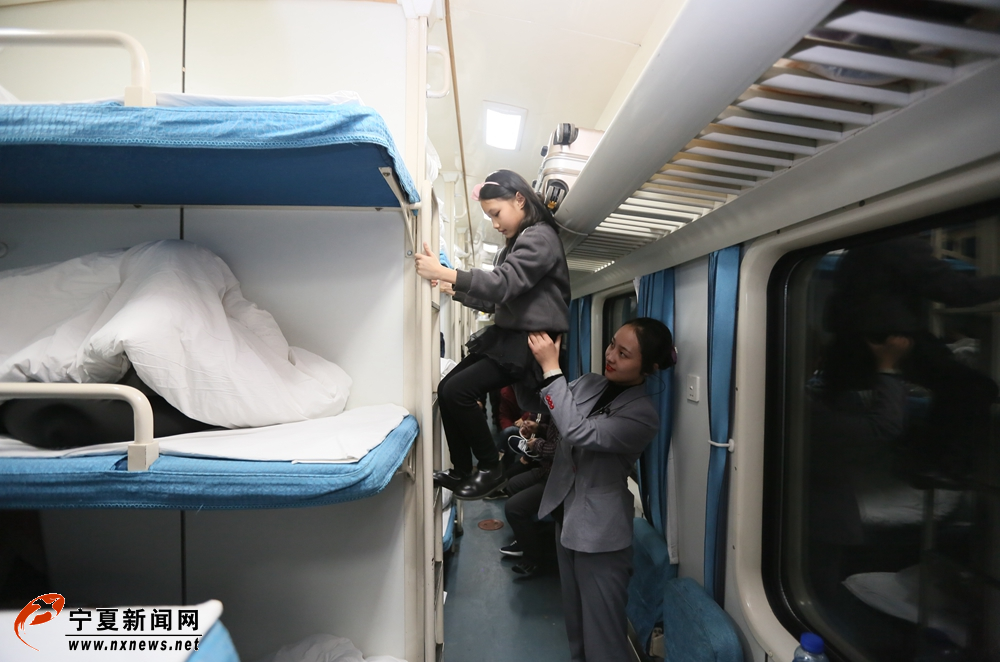 2月14日，在银川开往上海的K1331次列车上，列车员韩辉扶小朋友上铺梯。“小候鸟”是春运的一个特殊群体，列车员们在正常工作之余，照看好回家路上的孩子们是保障春运的特殊工作。