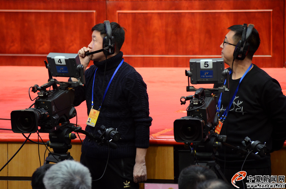 会议现场，宁夏广播电视台新闻中心记者董鹏（左）和他的同事在直播机位上工作。为确保直播万无一失，会议开始前1小时，他们已安装调试好所有的直播设备。