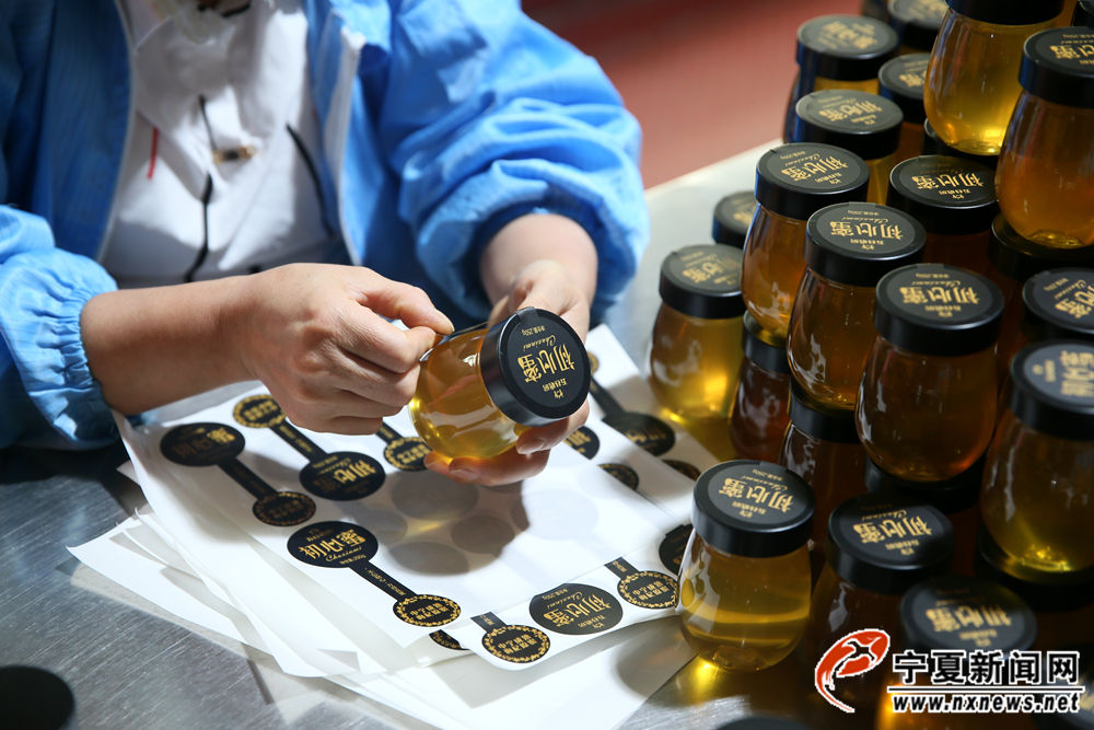 工人正在给成品贴标签。薛志刚给自家的花蜜起名“初心蜜”，他最常说的一句话，就是不忘初心、才有甜蜜。