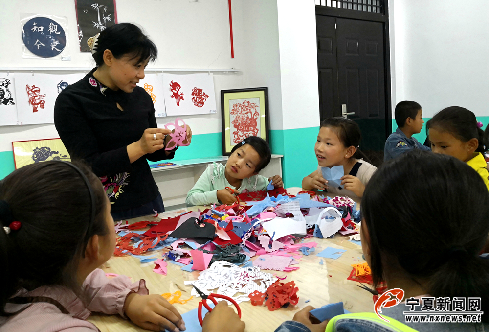 刘秋蓉教学生剪纸。丁塘镇中心小学注重学生德智体美劳全面发展，除正常文化课学习外，还开设了剪纸、美术、音乐、书法等课程。