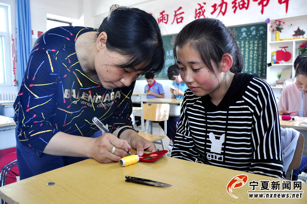 刘秋蓉教同心县特殊教育学校的孩子刺绣画样。她每周去给孩子们上四节刺绣课，为了不影响中心学校的正常教学，去特教学校授课的时间都安排在下午下班后。