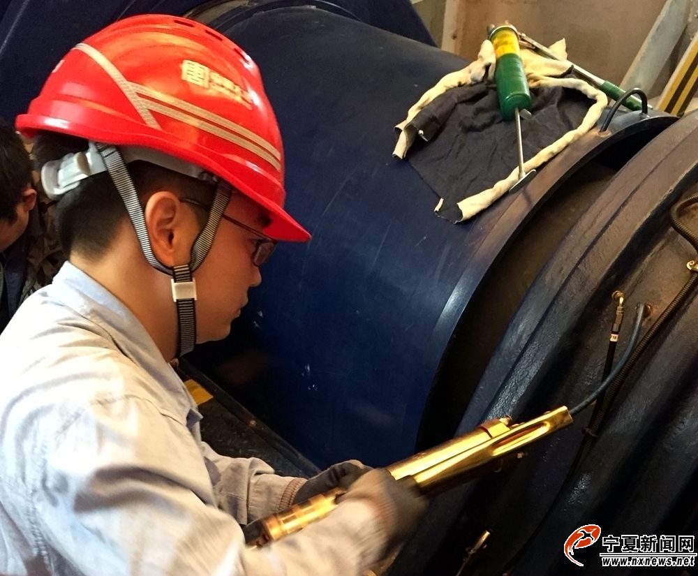 检修员曹东亮给风机主轴承添加润滑油脂，保证轴承润滑良好。