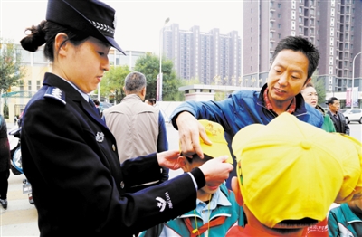 <p>　　全力推进社区警务改革，全面落实“一村（社区）一警”社区警务配置要求，让社区民警深度融入基层社会治理。图为公安部二级英模侯金知为放学后的小学生戴安全帽。</p>