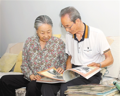 <p>　　吴赞国（右）和妻子翻看收录其摄影作品的画册。</p>