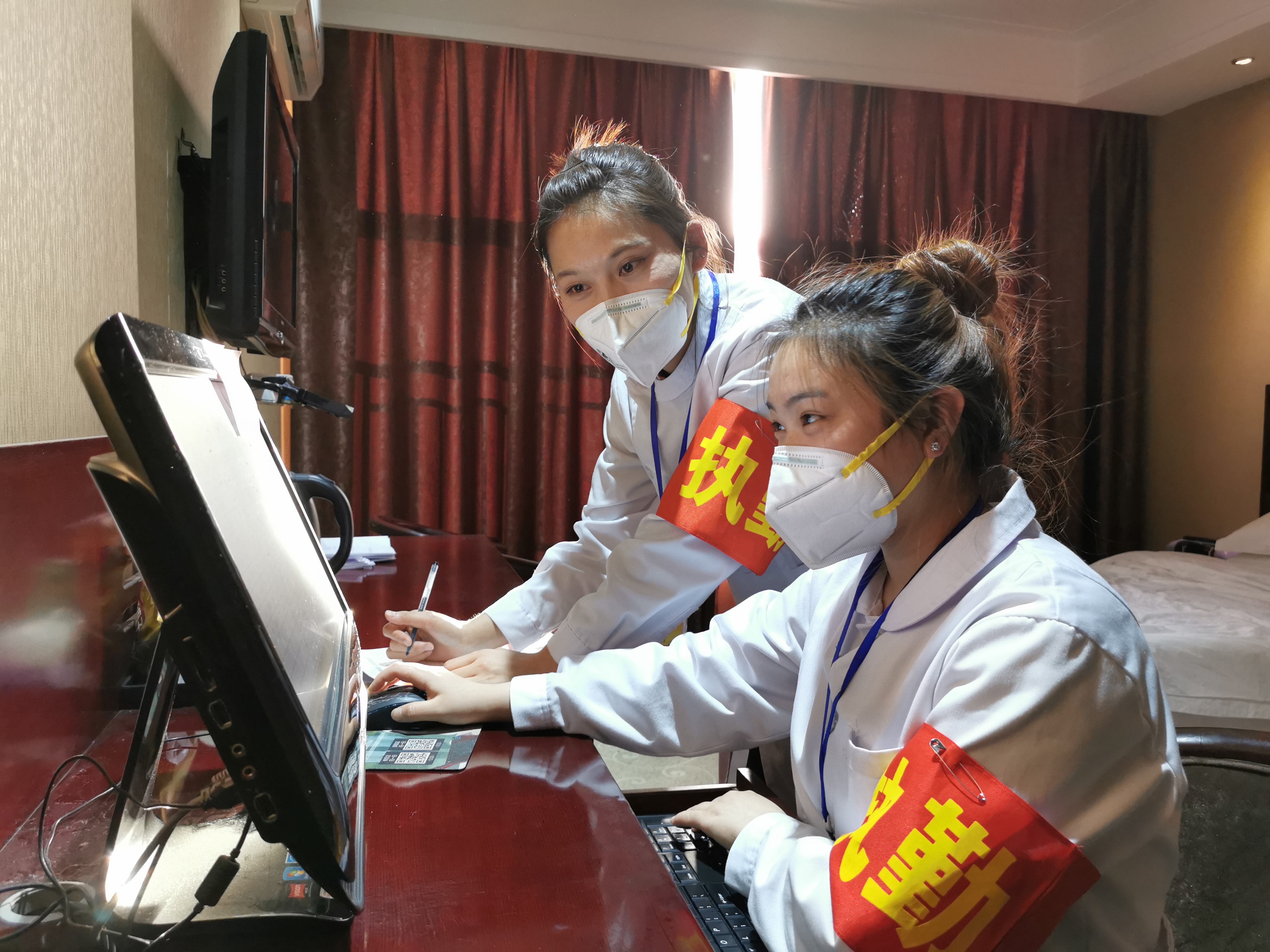 石嘴山市志愿者王玲，袁娇娇在集中隔离点登记刚测出的隔离人员体温。朱立杨摄。.jpg