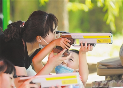 <p>　　一位小朋友与妈妈分享射击带来的乐趣。</p>