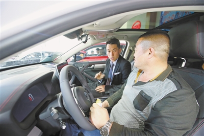 <p>　　　　销售人员向顾客介绍车辆内饰。本报记者　王洋　摄</p>