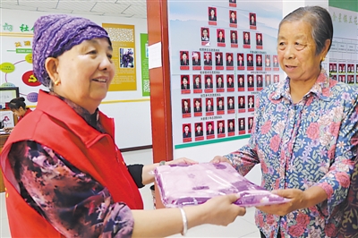 <p>　　王兰花（左）给辖区群众送去需要的物品。</p>